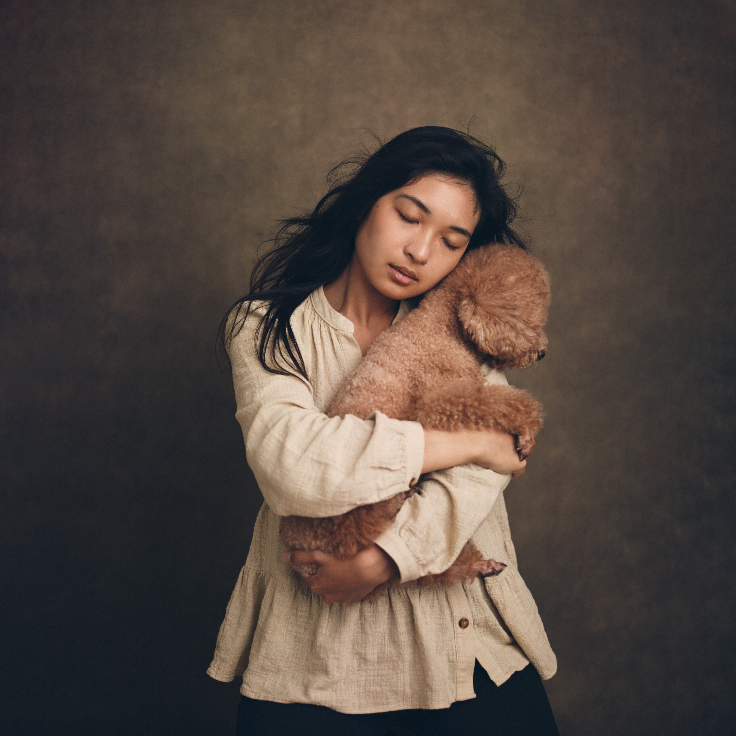 portrait photograph of a woman and her dog in her arms in a photography studio in Hong Kong