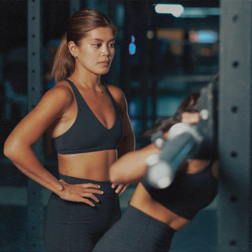 personal trainer in a hong kong gym spotting a woman lifting weights